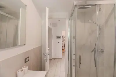 a white bathroom with a shower and a sink at San Pietro - moderno appartamento in Rome