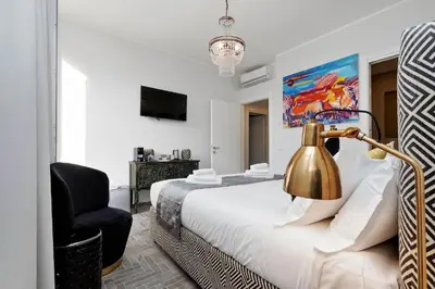 a bedroom with a bed with a lamp and a chair at Boutique Suites della Croce in Rome