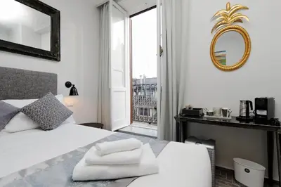 a bedroom with a white bed with a mirror and a window at Boutique Suites della Croce in Rome