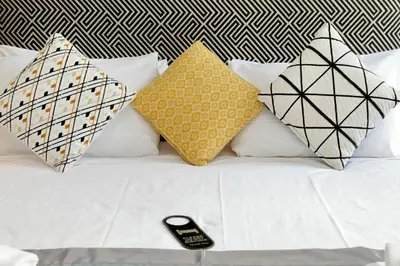 a bed with four pillows and a cell phone on it at Boutique Suites della Croce in Rome