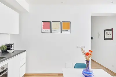 a white kitchen with a vase of flowers on a table at iFlat Lovely Modern Apartment in Rome