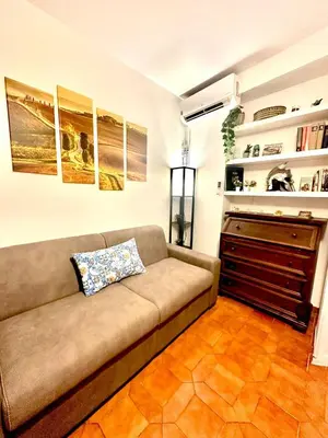 a couch in a living room with paintings on the wall at 150 meters from the Colosseum - Appartmento Gladiatore in Rome
