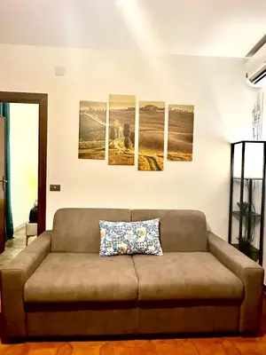a couch in a living room with four paintings on the wall at 150 meters from the Colosseum - Appartmento Gladiatore in Rome