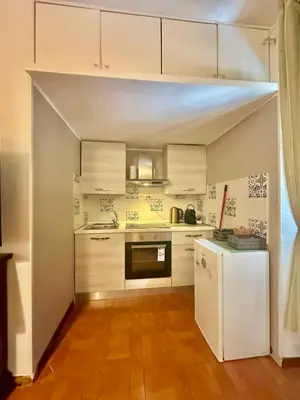 a kitchen with white cabinets and a white refrigerator at 150 meters from the Colosseum - Appartmento Gladiatore in Rome