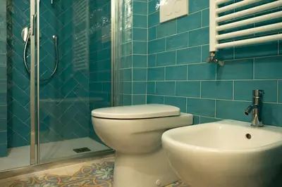 a blue tiled bathroom with a toilet and a sink at Farina 36 in Rome