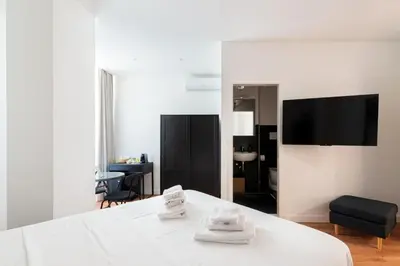 a bedroom with a white bed and a black chair at Roma Mia in Trastevere in Rome