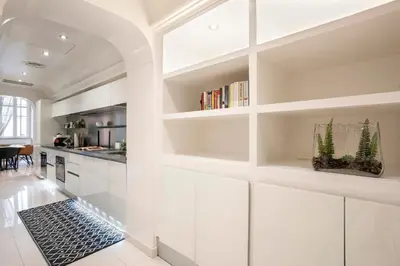 a white kitchen with white cabinets and bookshelves at Angelique Boutique in Rome