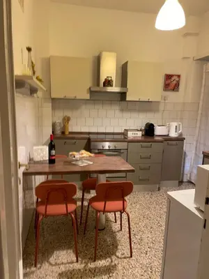 a kitchen with a wooden table and two red chairs at Ila Guest House in Rome