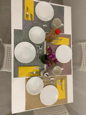 a table with white plates and yellow napkins at Lola Holiday Home, Roma Ostiense in Rome
