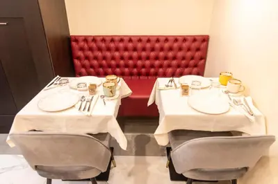 two tables in a restaurant with a red bench at Adelaide Suite Dreams in Rome