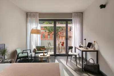 a bedroom with a bed and a balcony with a table at Bob W Rome Testaccio in Rome