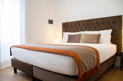 a bedroom with a large bed with white sheets and pillows at Michelangelo Vatican Guest House in Rome
