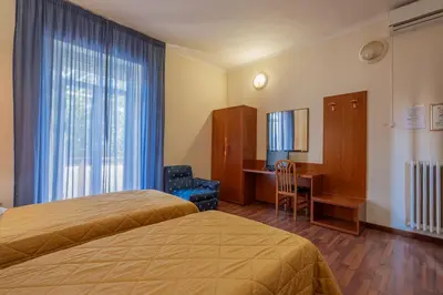 a hotel room with two beds and a desk at Hotel Monte Verde in Rome