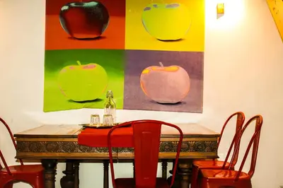 a table with chairs and paintings of apples on the wall at DGVatican in Rome