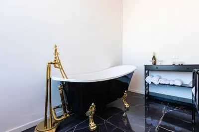 a bath tub in a bathroom with a black floor and a sink at Colosseo View Atmosphere by Rental in Rome in Rome
