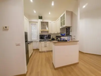 a kitchen with white cabinets and a wooden floor at Chic Modern 2-Bedroom near Metro in Rome