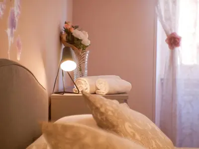 a bedroom with a vase of flowers and towels on a table at Chic Modern 2-Bedroom near Metro in Rome