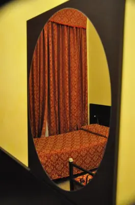 a mirror reflecting a bedroom with a bed and a curtain at Funny Palace Hostel in Rome