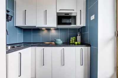 a kitchen with white cabinets and blue tiles at BDC - Rome with a view! in Rome