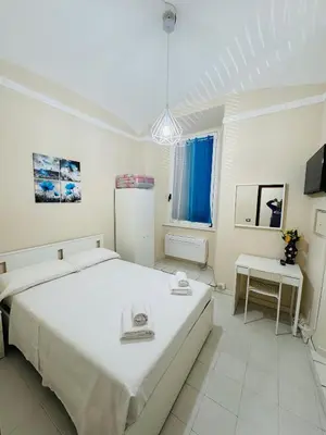 a white bedroom with a large bed and a table at MILLE PARADISO in Rome