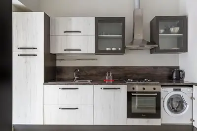 a kitchen with white cabinets and a washing machine at Colosseo Road by Hili in Rome