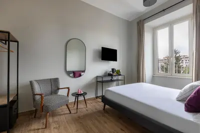 a bedroom with a bed and a chair and a mirror at Colosseo Road by Hili in Rome