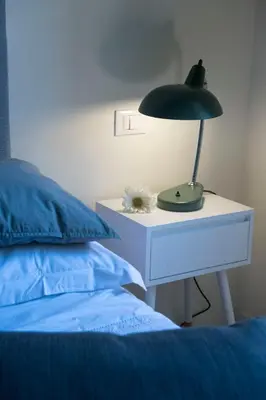 a lamp on a night stand next to a bed at FUORI dal TEMPO Roma Trastevere in Rome