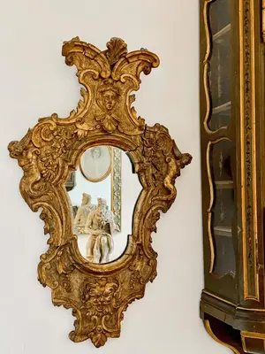 a gold mirror hanging on a wall with a vase at Farnese Apartment Navona Historic Center in Rome