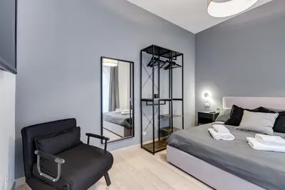 a bedroom with a bed and a chair and a mirror at Classy 2-bdr in Termini district in Rome