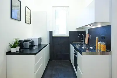 a kitchen with white cabinets and a black counter top at Suite 52 Trastevere in Rome
