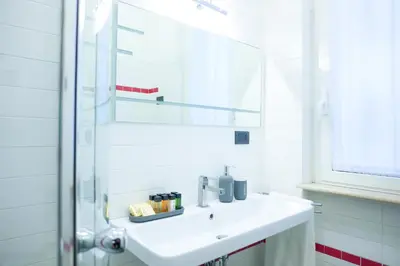 a white bathroom with a sink and a mirror at Suite 52 Trastevere in Rome