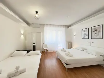 two beds in a bedroom with white walls and wood floors at Golden Essence Apartment - terrace & metro in Rome
