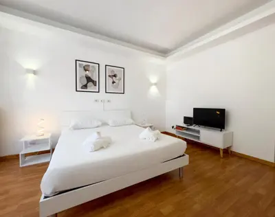 a white bedroom with a bed and a flat screen tv at Golden Essence Apartment - terrace & metro in Rome