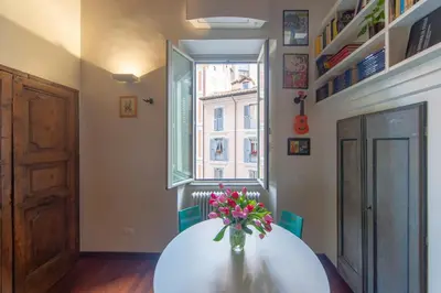 a room with a white table with a vase of flowers at Saint Louis Penthouse, cozy little apartment next to Pantheon in Rome