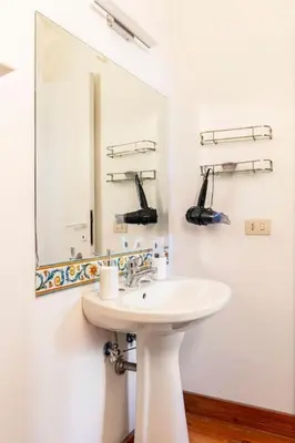 a white bathroom with a sink and a mirror at Delizioso appartamento a Trastevere in Rome
