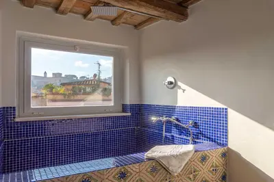 a bathroom with a window and a blue tiled tub at Lusso e panorama senza paragoni, Loft Trastevere in Rome