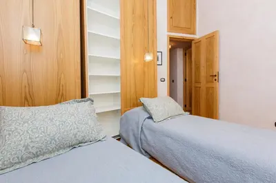 a bedroom with two beds and a book shelf at Habitat's Navona 4BR Apartment in Rome