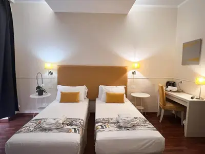 a hotel room with two beds and a desk at Caesar Place in Rome