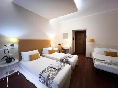 a hotel room with two beds and a desk at Caesar Place in Rome