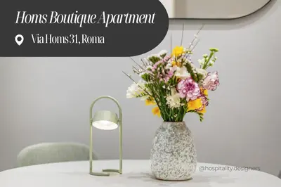 a vase of flowers on a table with a lamp at Homs Boutique Apartment in Rome
