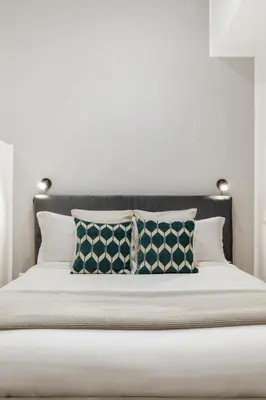 a bed with pillows on it with a white wall at Homs Boutique Apartment in Rome
