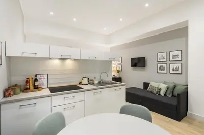 a kitchen with white cabinets and a couch in a room at Homs Boutique Apartment in Rome