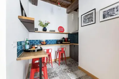 a small kitchen with red stools and blue tiles at Trastevere 68 Stylish Apartment in Rome