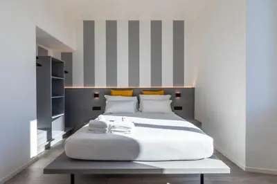 a large white bed in a room with striped walls at Veneto Suite Roma in Rome