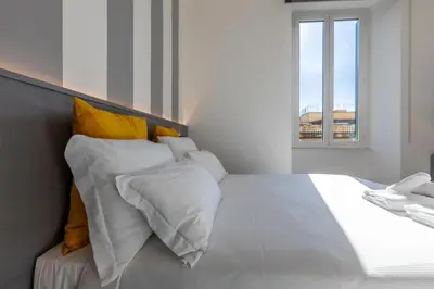 a bedroom with a white bed with yellow pillows at Veneto Suite Roma in Rome