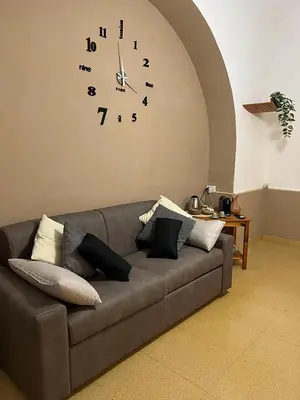 a couch in a living room with a clock on the wall at Sapri Apartment - Castro Pretorio by GHOR in Rome