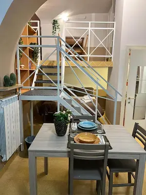 a dining room with a table and a spiral staircase at Sapri Apartment - Castro Pretorio by GHOR in Rome