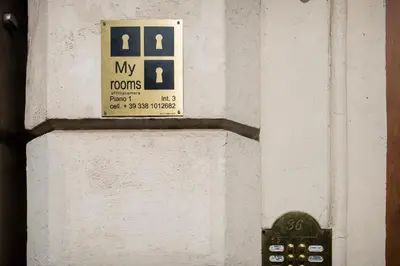 a sign on the side of a white wall at My Rooms in Rome