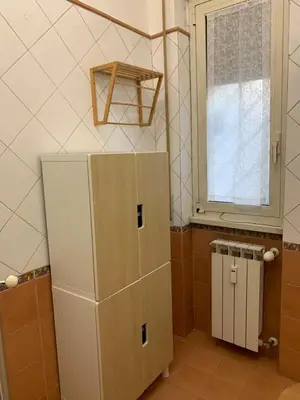 a bathroom with a white refrigerator and a window at Valerie house Garbatella in Rome