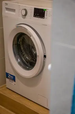a white washing machine sitting on a wooden shelf at Little Blue Apartment in Rome